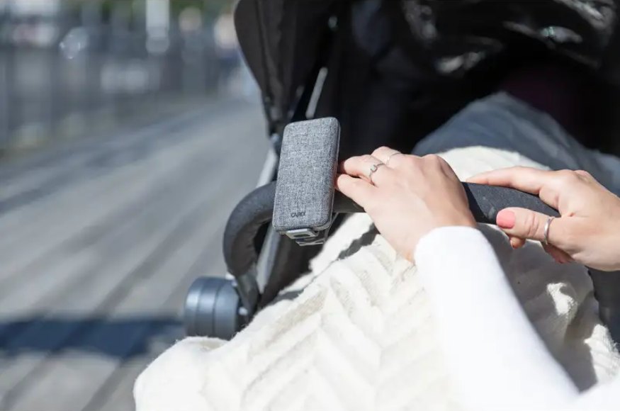 Hånd på barnevognens styr, hvor en grå CAPiDi-babyenhed sidder spændt fast